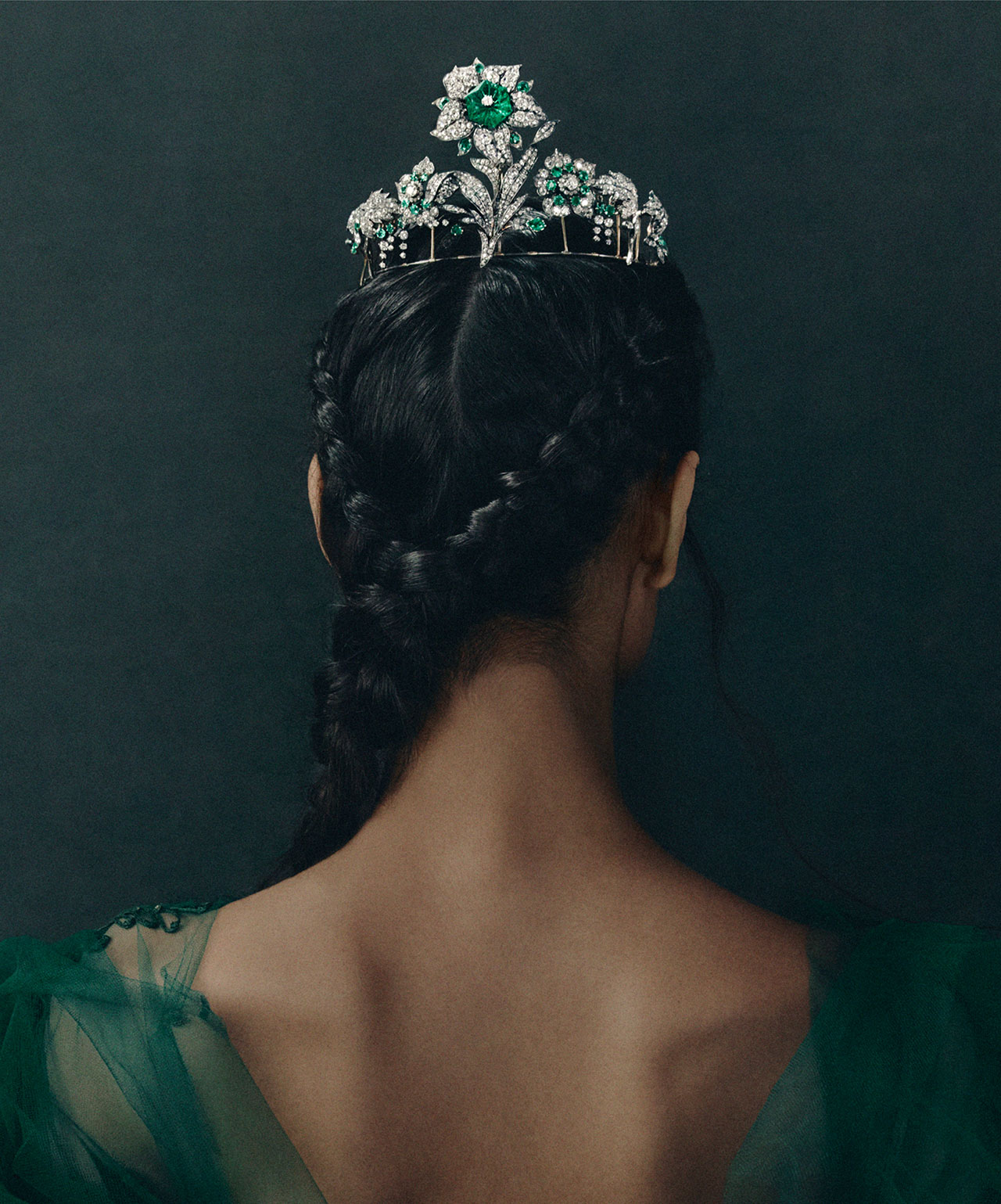 Back view of a woman wearing an emerald and diamond tiara.